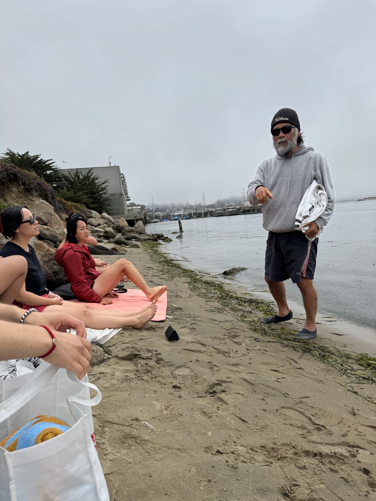 Russ talking with members sitting on the sand at the water's edge before a dip