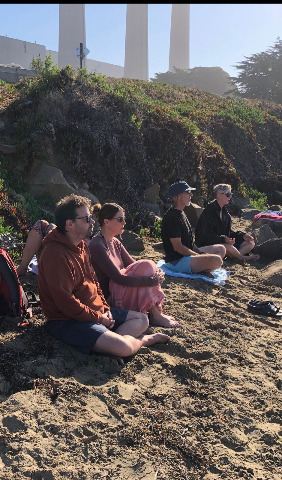 Members sitting together on the beach for breath work before getting in the water